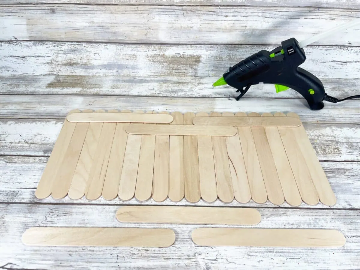 Homemade popsicle sticks with a glue gun on a wooden table.