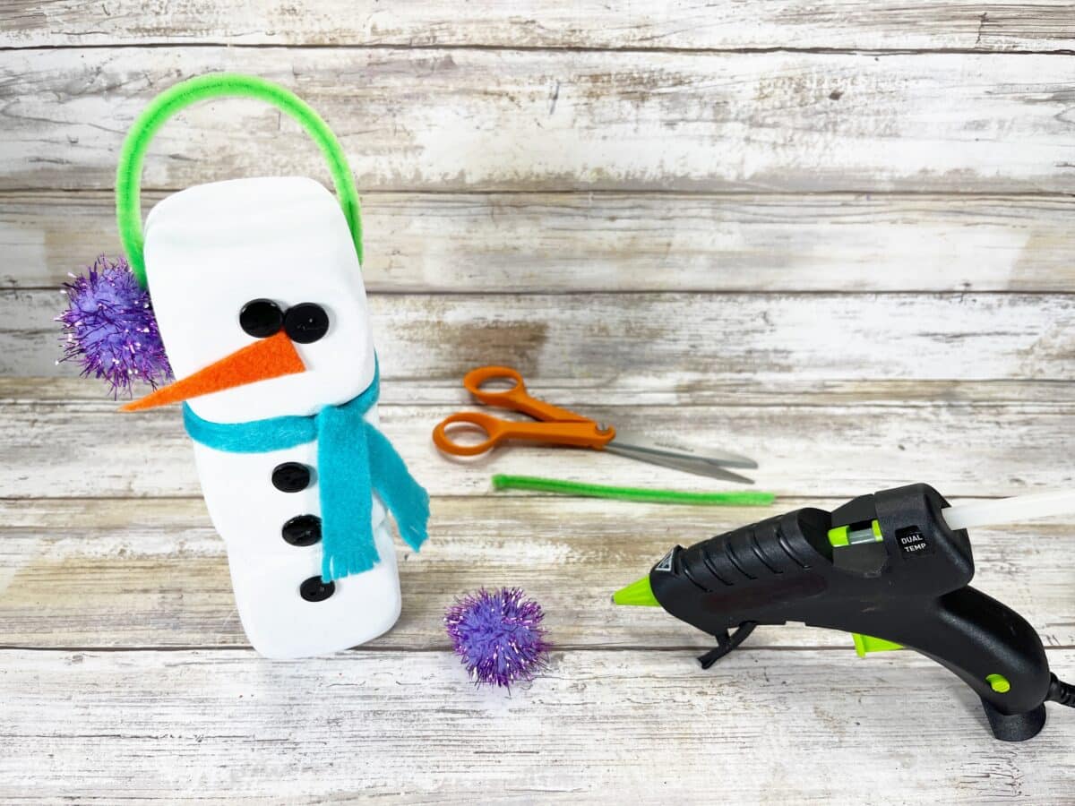 A snowman craft with a glue gun and pom poms.