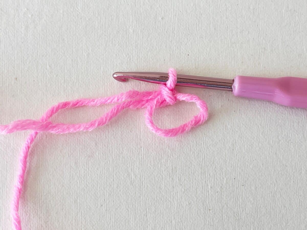 A pink crochet hook with a pink yarn.