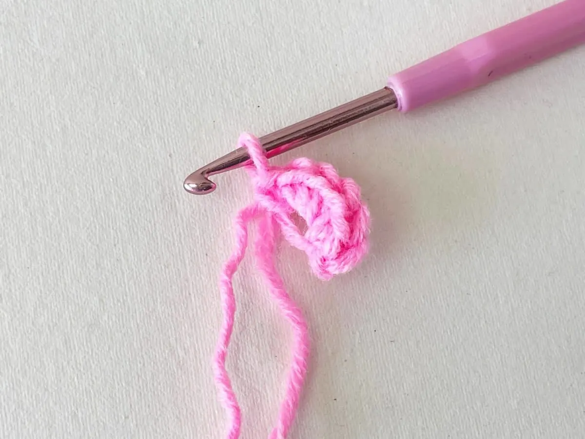 A pink crochet hook on a white surface.