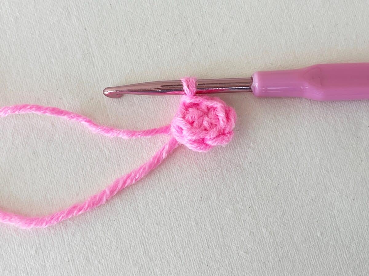 A pink crochet hook with a pink flower on it.