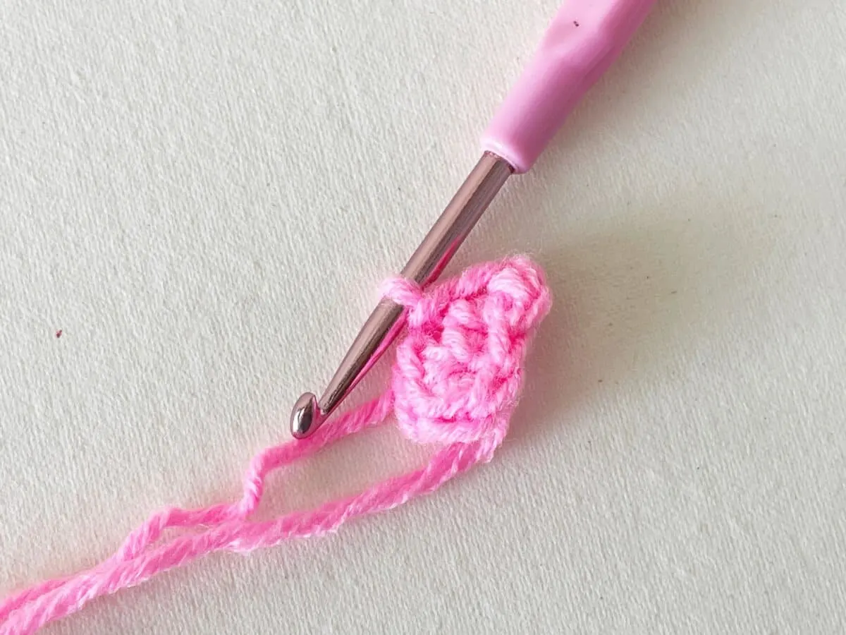 A pink crochet hook with a pink crochet stitch.