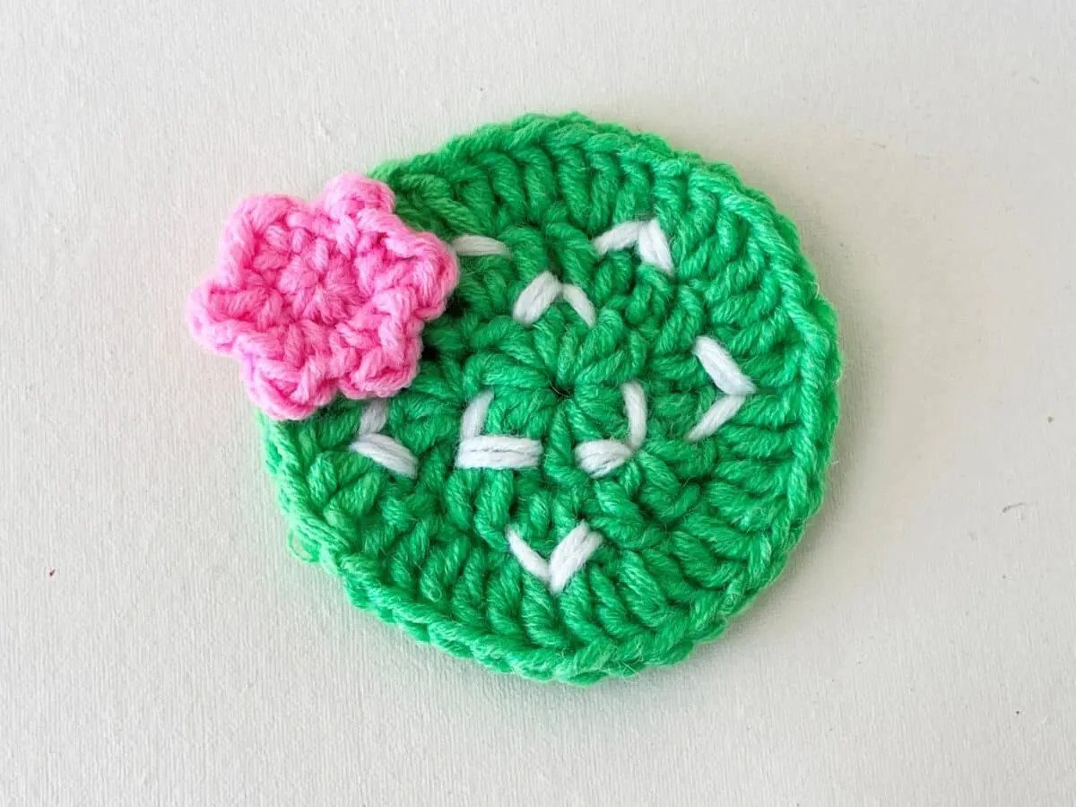 Crocheted cactus brooch with pink flower.