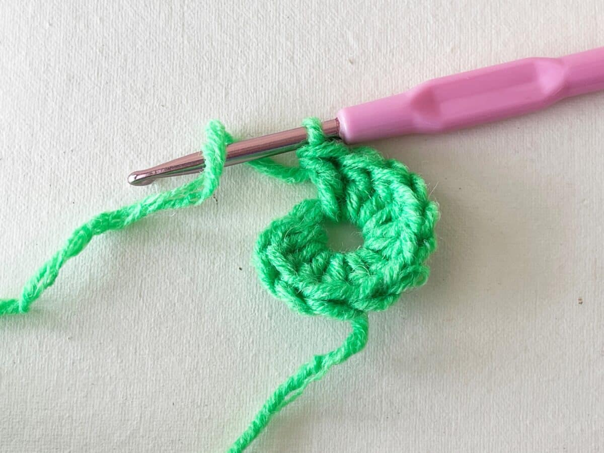 A green crochet hook with a pink crochet hook.