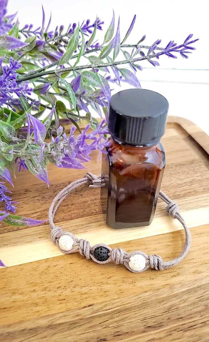 DIY Essential Oil Bracelet with a lavender essential oil on a wooden cutting board.