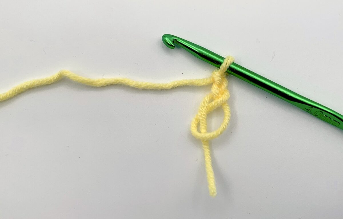 Round 1 - Step 1.1 A green crochet hook with a yellow yarn.