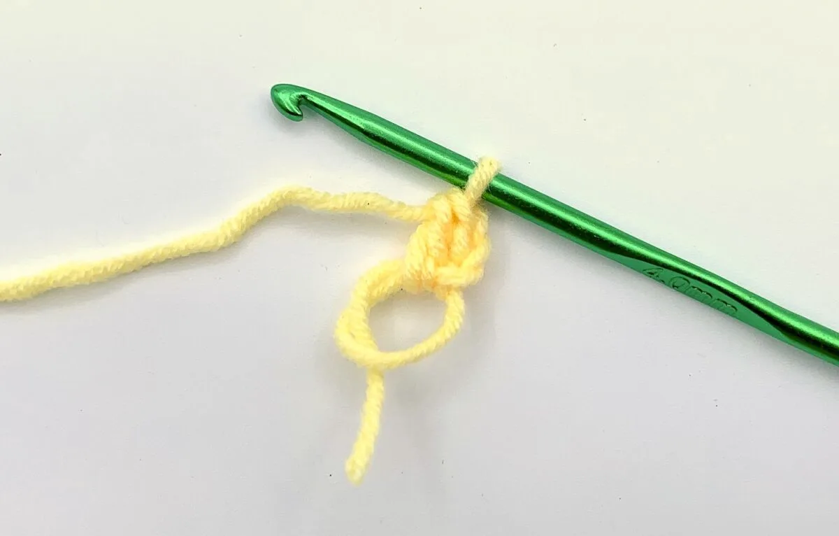 Round 1 - Step 2 A green crochet hook with a yellow yarn.