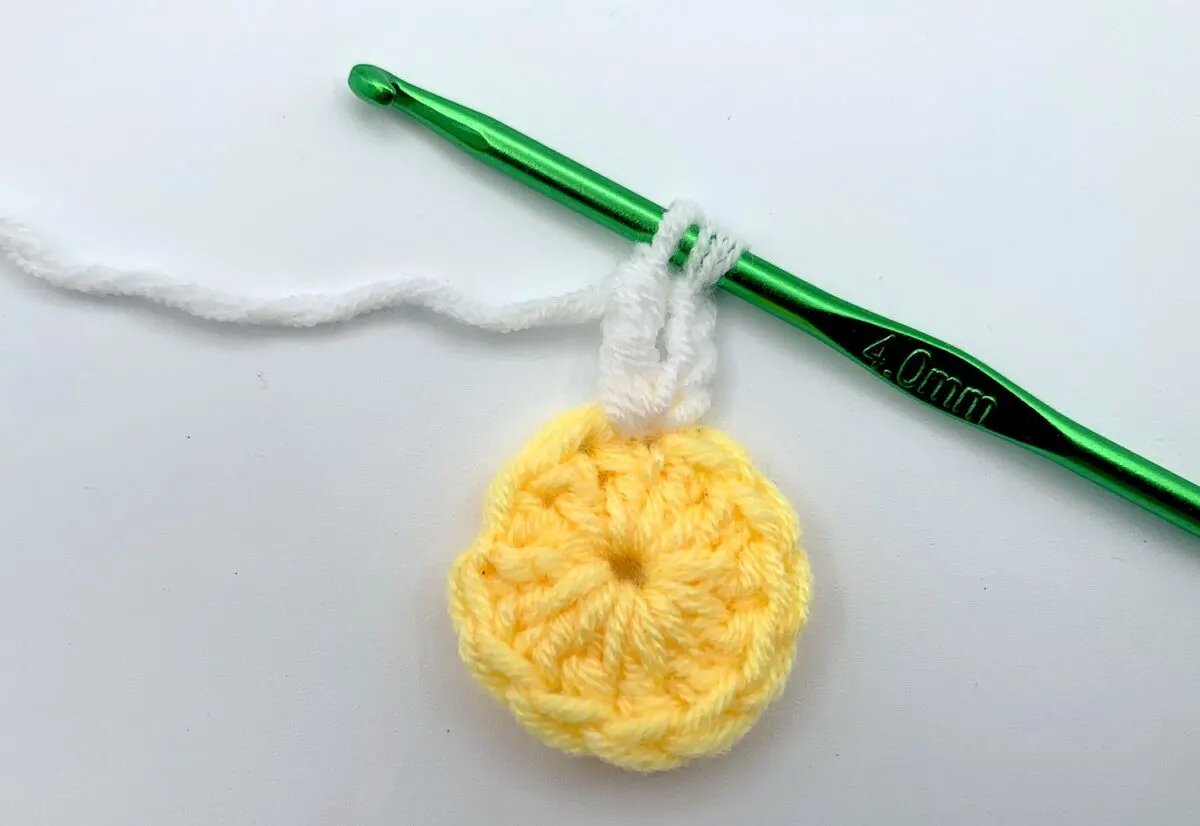 Round 2 - Step 2 A crocheted lemon with a green crochet hook.