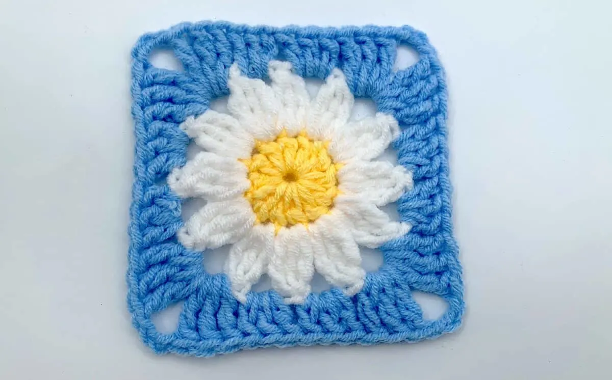 Round 3 - Step 14 A crocheted square with a daisy in the center.