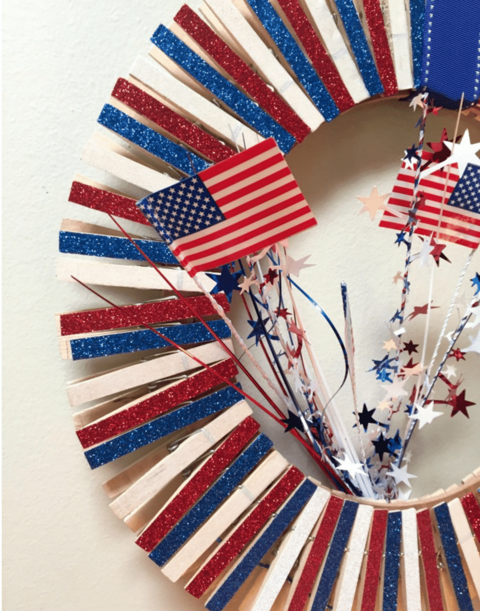 A patriotic Fourth of July wreath decorated with the colors of the American flag and adorned with stars and miniature flags.