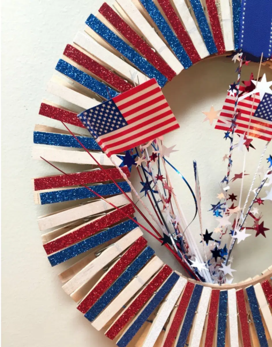A patriotic Fourth of July wreath decorated with the colors of the American flag and adorned with stars and miniature flags.