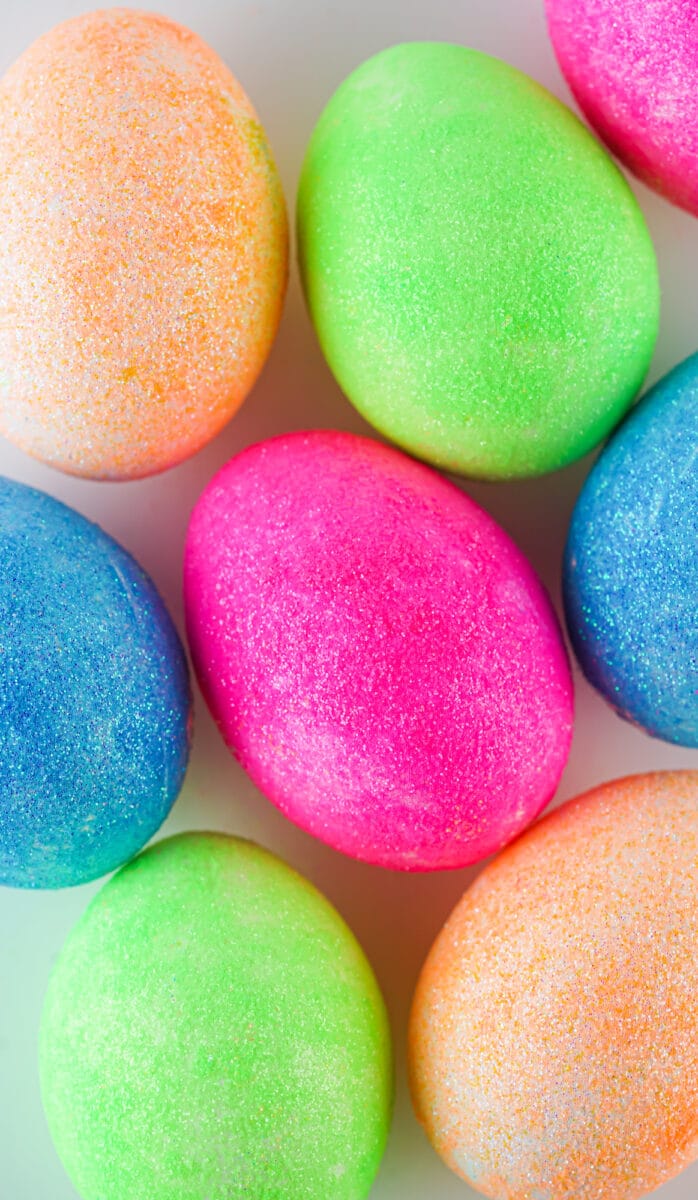 Colorful DIY glitter-coated Easter eggs arranged closely together.