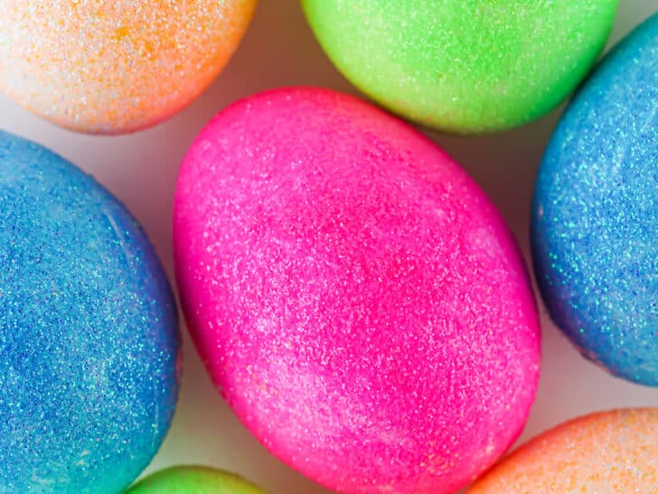 Colorful DIY glitter-coated Easter eggs arranged closely together.