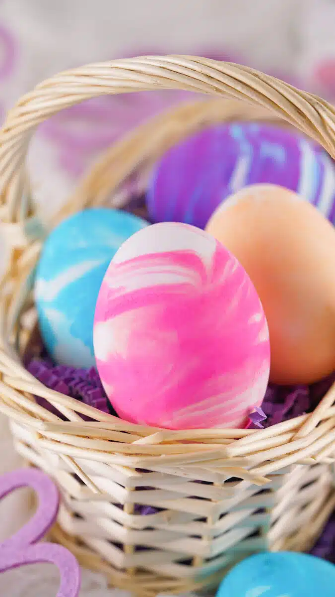 A basket containing colorful Easter eggs with a prominent pink and white Cool Whip egg in the foreground.