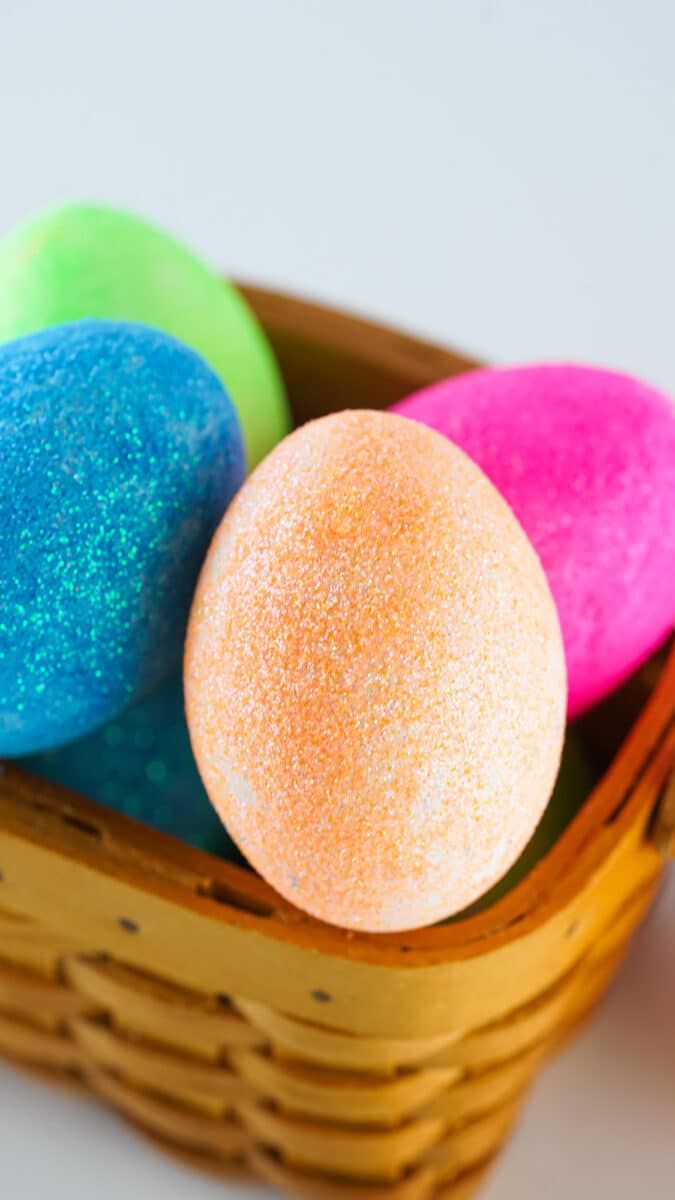 Colorful DIY glitter-covered Easter eggs in a wicker basket.