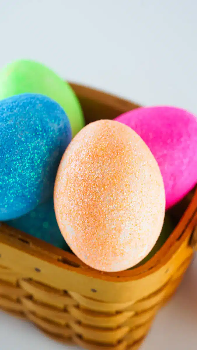 Colorful DIY glitter-covered Easter eggs in a wicker basket.