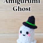 A small amigurumi ghost with pink cheeks and a black witch hat, displayed on a wooden surface. Text reads: "Free Crochet Pattern! Amigurumi Ghost. SingleGirlsDIY.com.