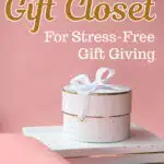 A pink background with a white gift box tied with a ribbon, placed on white boxes. Text reads: "Why You Need a Gift Closet for Stress-Free Gift Giving." SingleGirlsDIY.com.