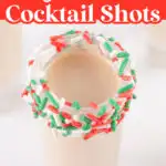 A sugar cookie cocktail shot with a rim decorated with red, green, and white sprinkles.