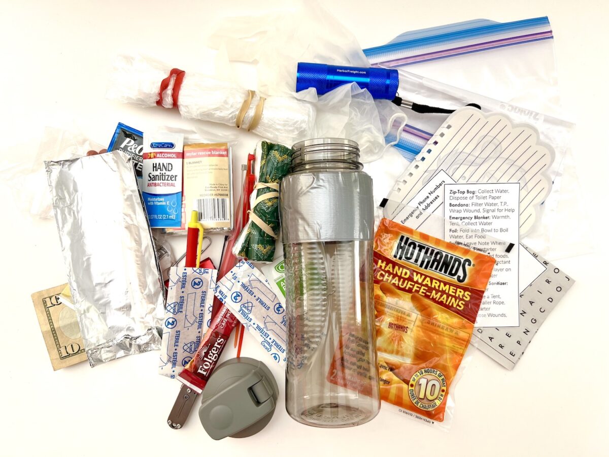 A collection of emergency preparedness items including a water bottle, hand warmers, sanitizer, rope, bandages, flashlight, food, and dollar bills, arranged on a white background.