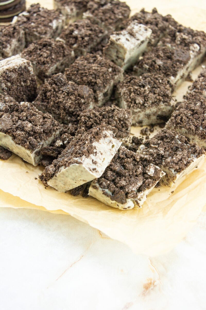 Rectangular Oreo cheesecake bars with crumbly tops are arranged on parchment paper.