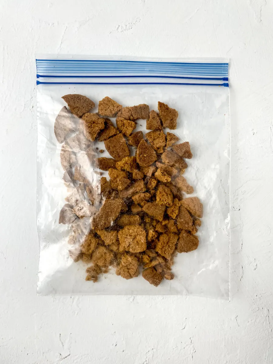 A clear plastic bag containing brown crumbled pieces on a white surface.