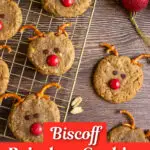 Cookies shaped like reindeer with pretzel antlers and red candy noses on a cooling rack, with holiday ornaments nearby. Text reads: "Biscoff Reindeer Cookies Recipe".