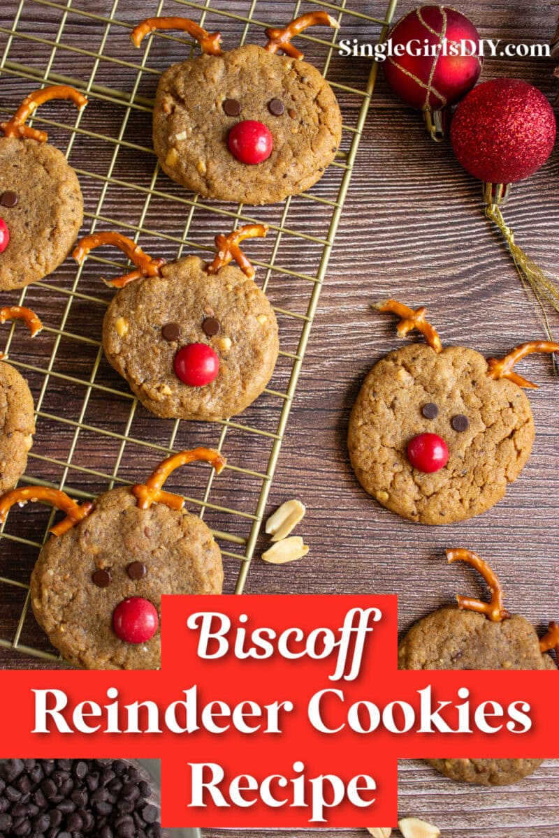 Cookies shaped like reindeer with pretzel antlers and red candy noses on a cooling rack, with holiday ornaments nearby. Text reads: "Biscoff Reindeer Cookies Recipe".