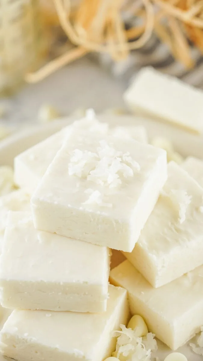 A stack of creamy white squares with shredded coconut on top, arranged on a plate.