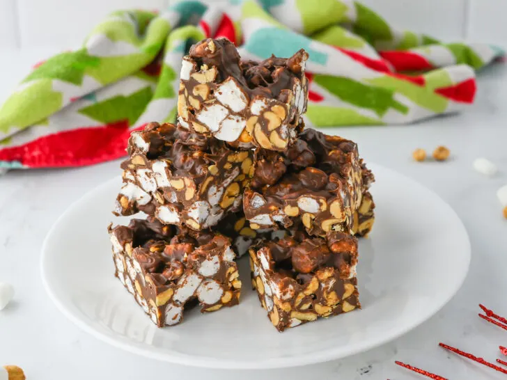 A plate of chocolate-covered marshmallow and peanut clusters, with a colorful towel in the background.