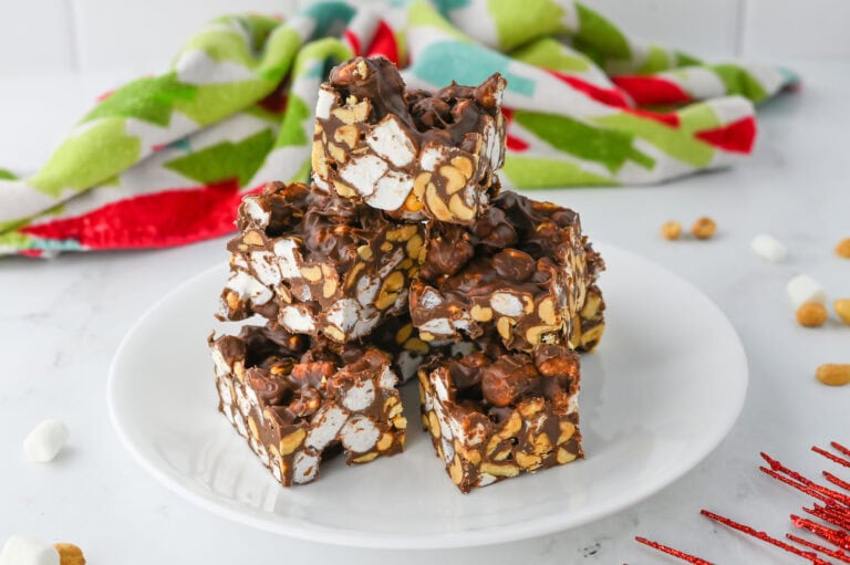 A plate of chocolate-covered marshmallow and peanut clusters, with a colorful towel in the background.