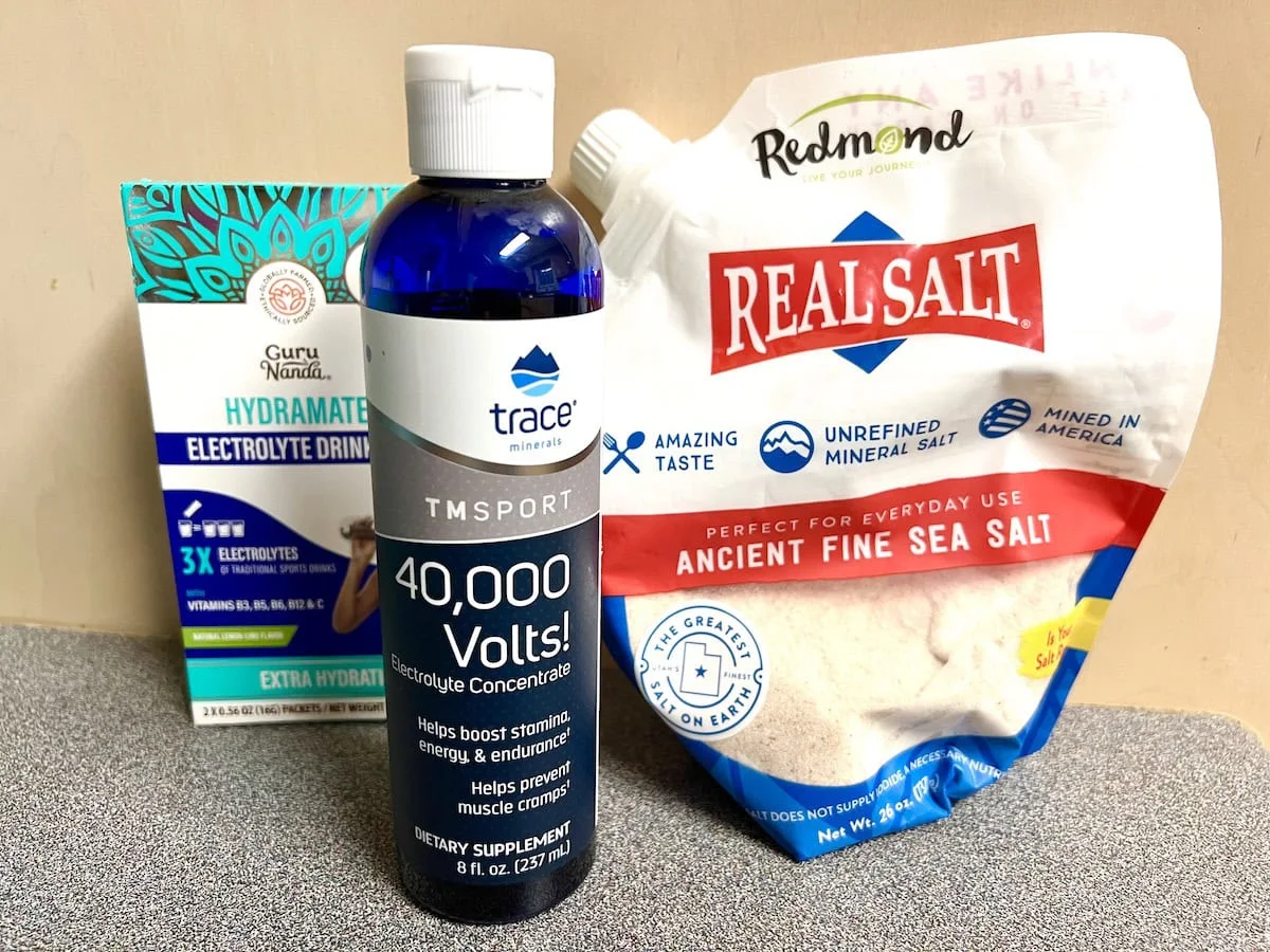 A display of electrolyte supplement products, including a 40,000 Volts! liquid in a blue bottle, Real Salt in a white bag, and Guru Nanda Hydramate Electrolyte Drink Mix in a box.