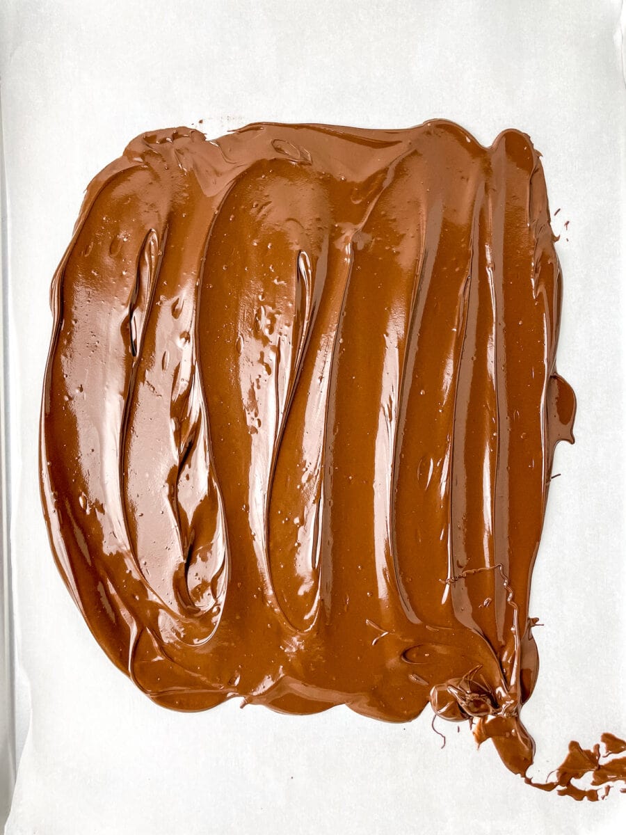 Smooth spread of melted chocolate on white parchment paper.