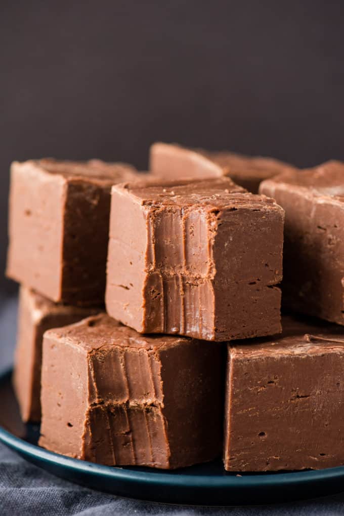 A stack of decadent chocolate fudge squares rests on a dark plate, showcasing the richness of homemade fudge recipes.