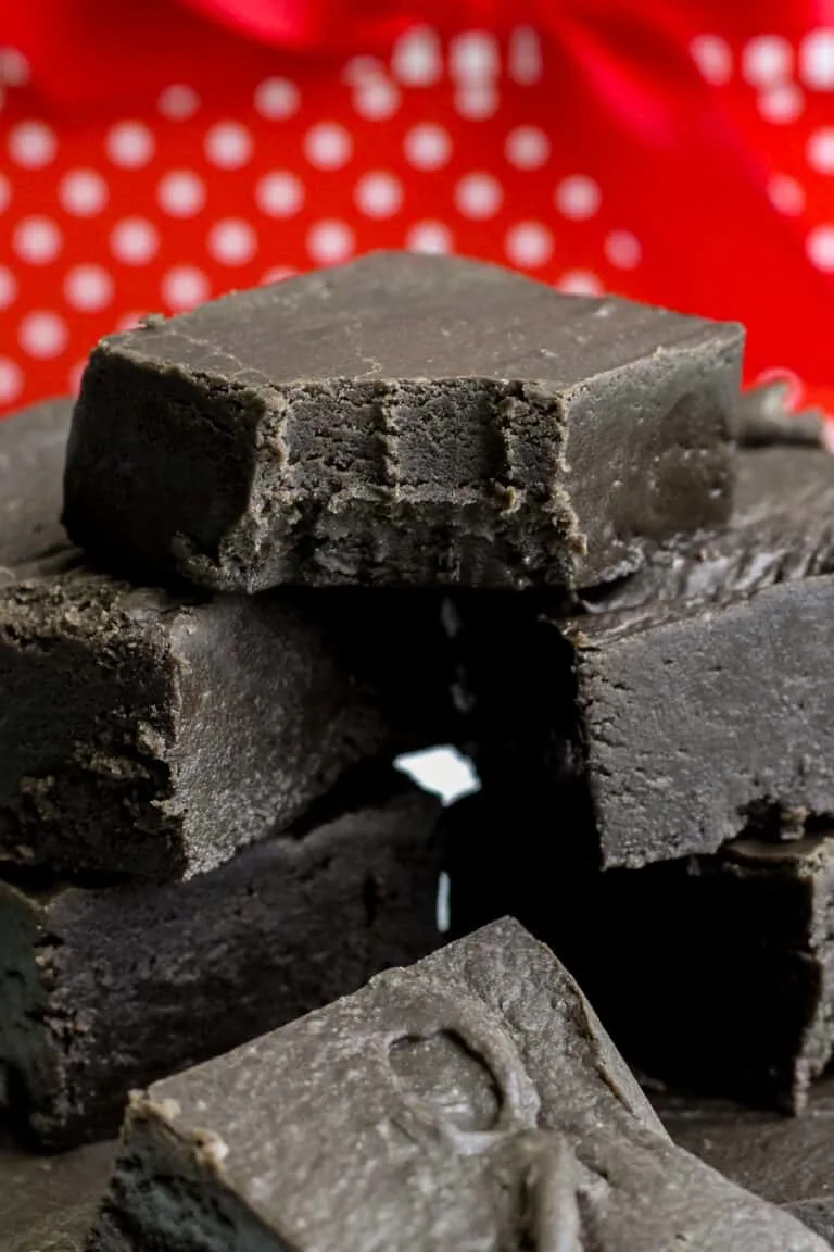 A tempting stack of black fudge squares, each with enticing bite marks, set against a playful red polka dot background. These treats might just inspire your next homemade fudge recipe adventure.