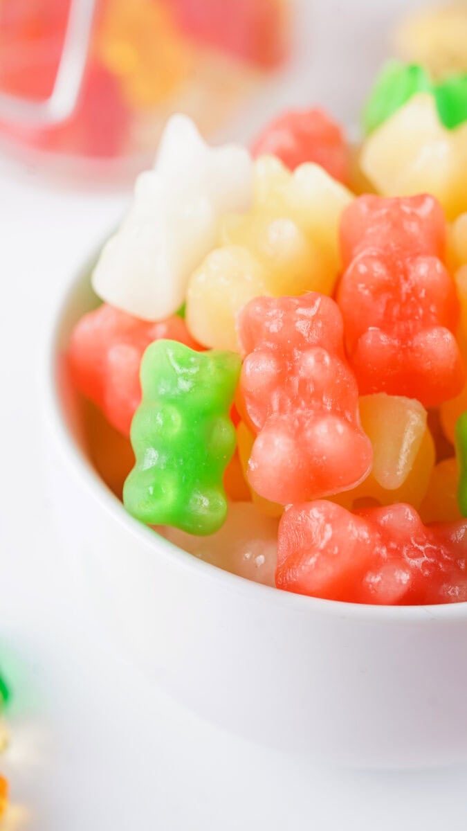 A bowl filled with colorful gummy bears, including red, green, and white candies.