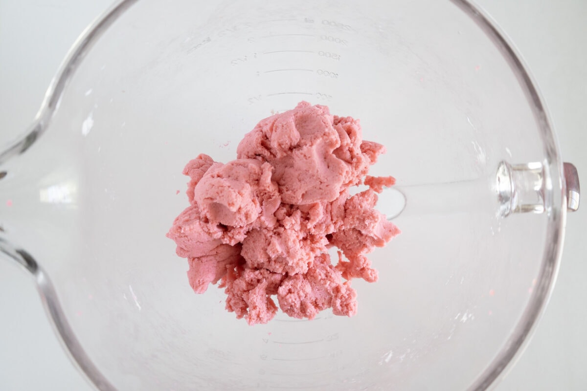 Pink dough in a clear mixing bowl viewed from above.