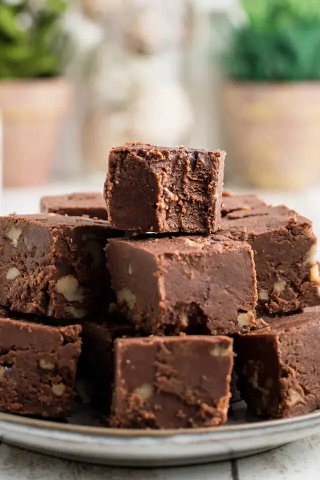 A plate of chocolate fudge squares stacked neatly, with visible nuts inside the pieces.