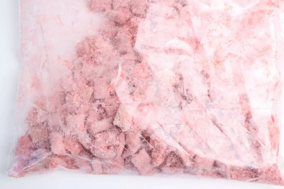 A sealed plastic bag filled with small, frozen pink chunks.