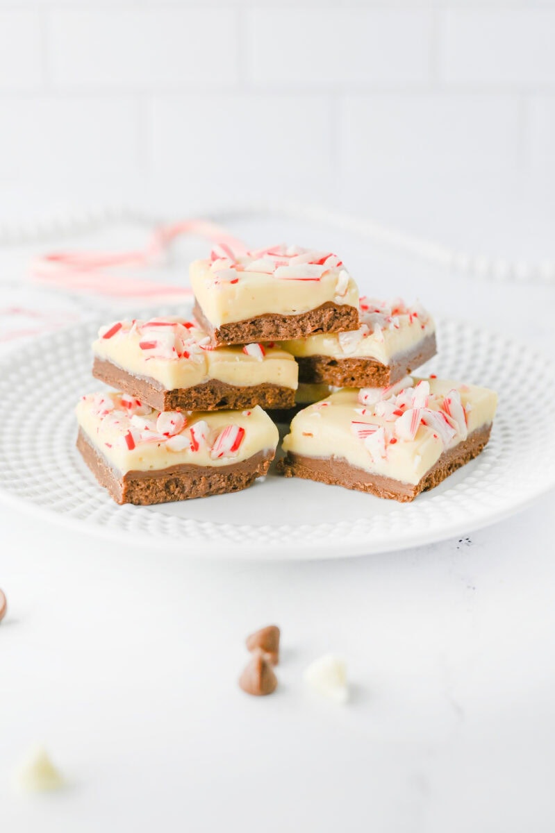 A stack of chocolate peppermint bark pieces on a white plate, topped with crushed candy canes.