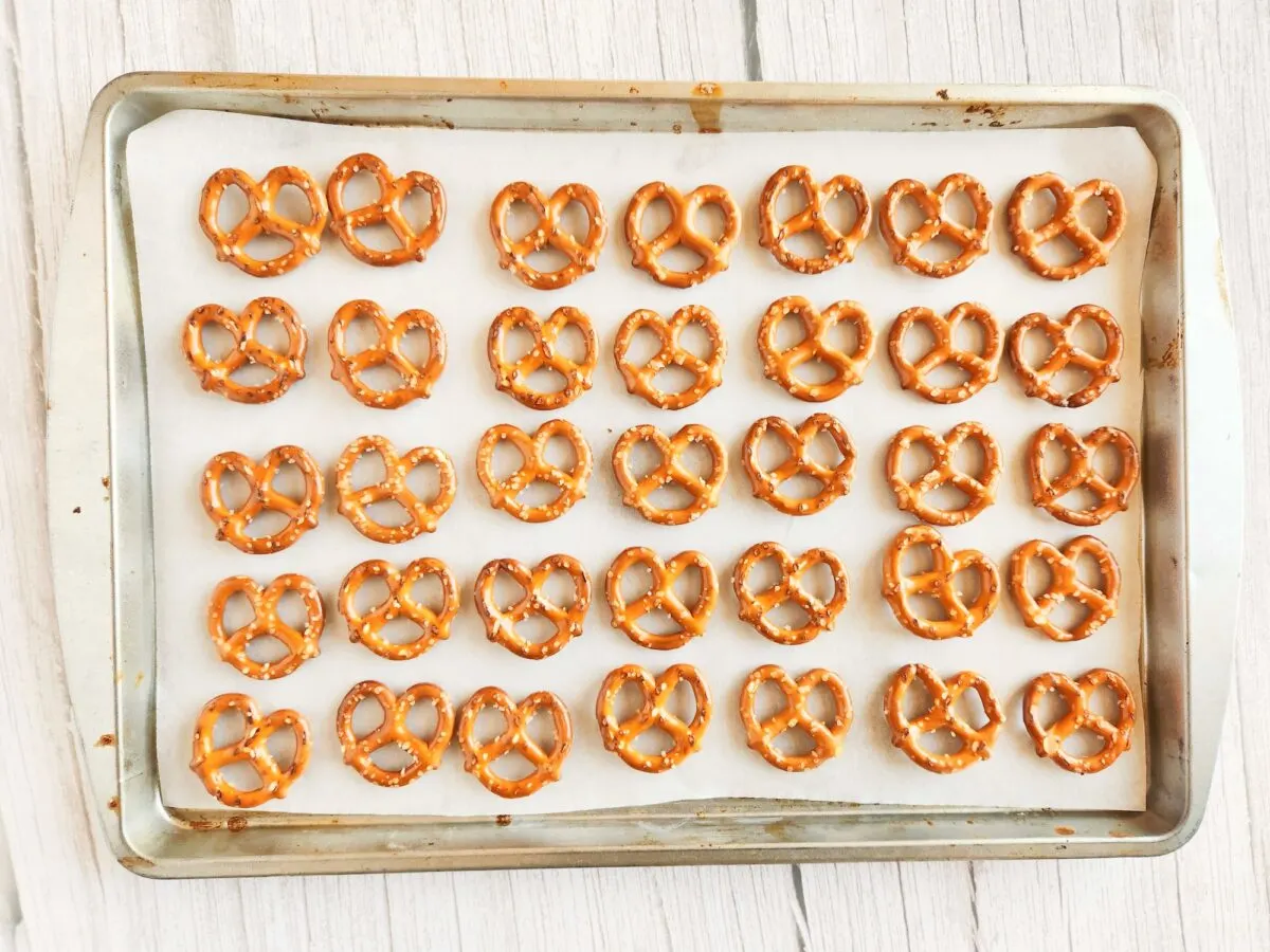 A baking tray with 35 small pretzels arranged in rows on parchment paper.