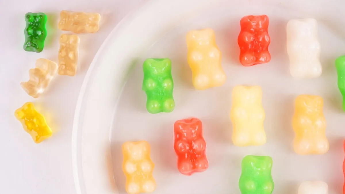 Colorful gummy bears on a white plate and surface.