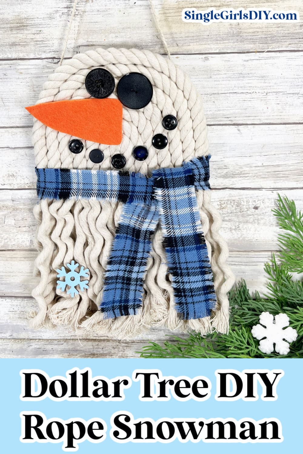 DIY rope snowman with button eyes and carrot nose, wearing a blue plaid scarf. Snowflake decoration and evergreen branch at the bottom.