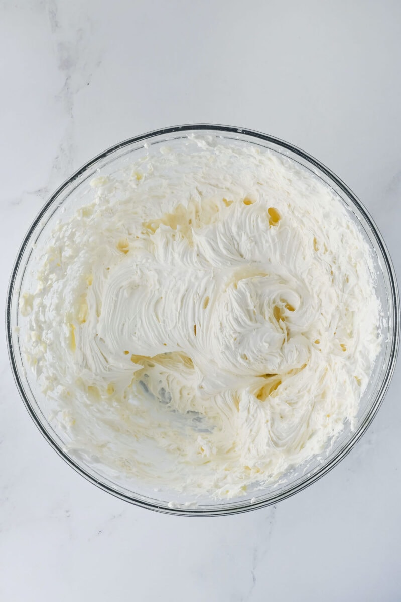 A glass bowl filled with whipped cream on a marble surface.