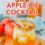 A glass of apple pie cocktail with ice, garnished with apple slices and a cinnamon stick, sits on a wooden surface next to fresh apples and cinnamon sticks. Discover the bold flavor of Fireball Whisky in every sip of this apple pie cocktail.