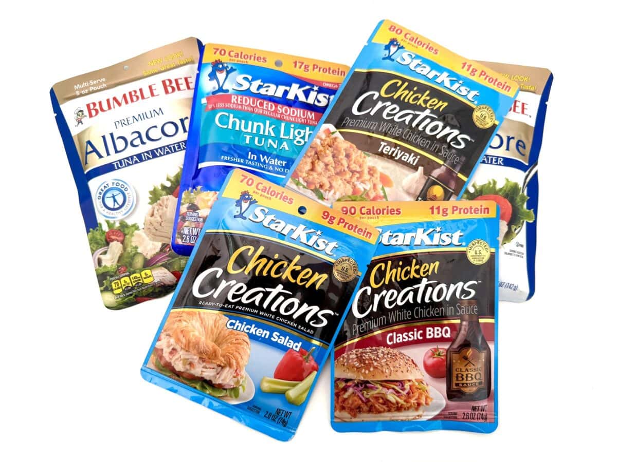 Five assorted pouches of Bumble Bee and StarKist brand tuna and chicken, featuring different flavors such as Teriyaki, Classic BBQ, and Chicken Salad, arranged on a white background.