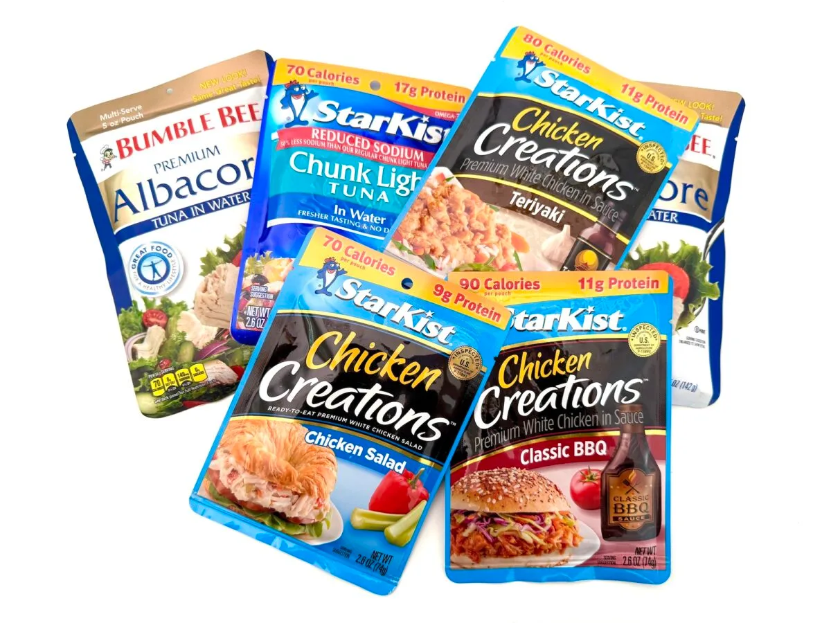 Five assorted pouches of Bumble Bee and StarKist brand tuna and chicken, featuring different flavors such as Teriyaki, Classic BBQ, and Chicken Salad, arranged on a white background.