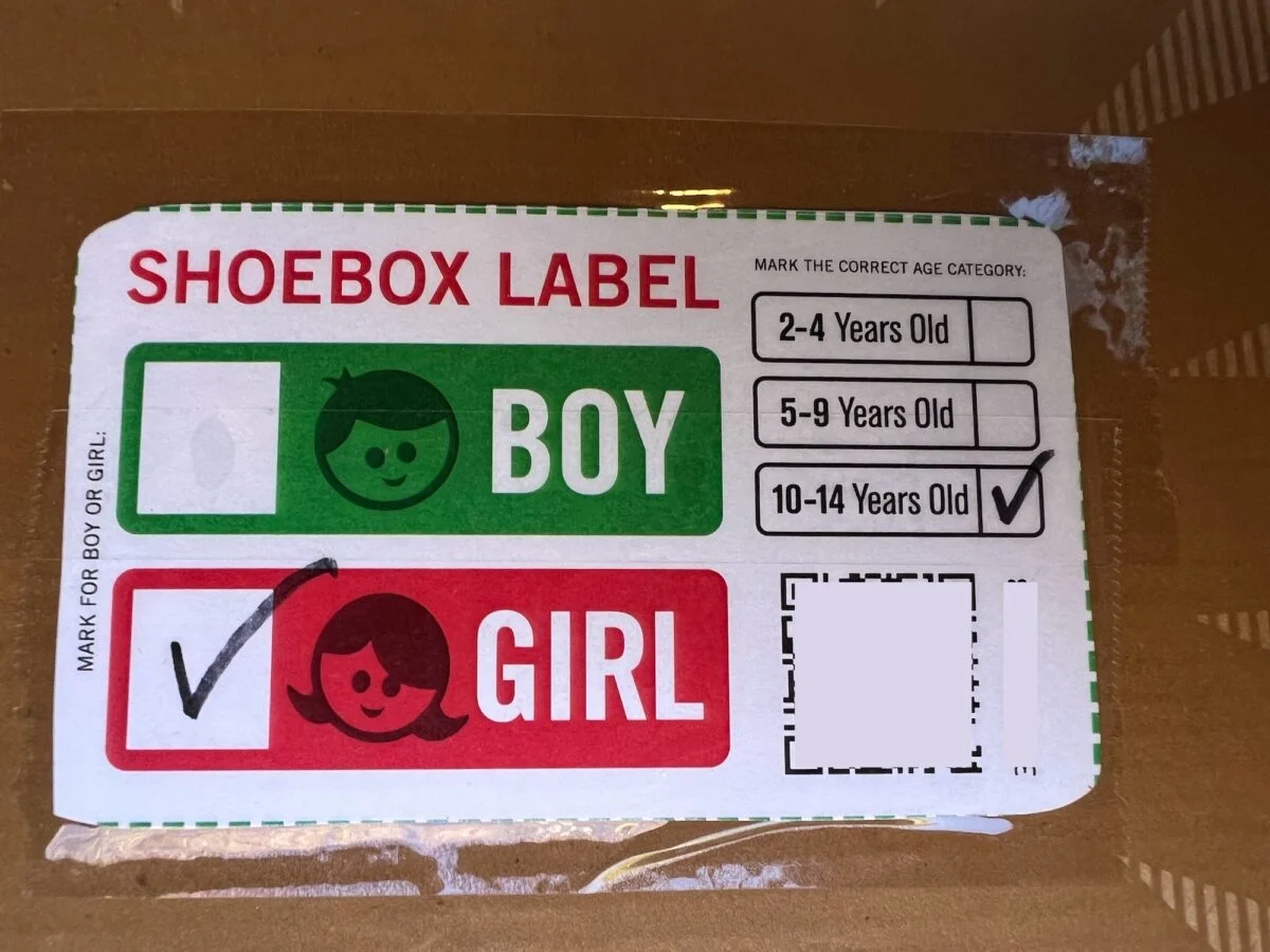 A shoebox label for Operation Christmas Child with boxes for "Boy" and "Girl," the "Girl" box checked. Age categories listed, with "10-14 Years Old" marked. A blank space for additional information is visible.