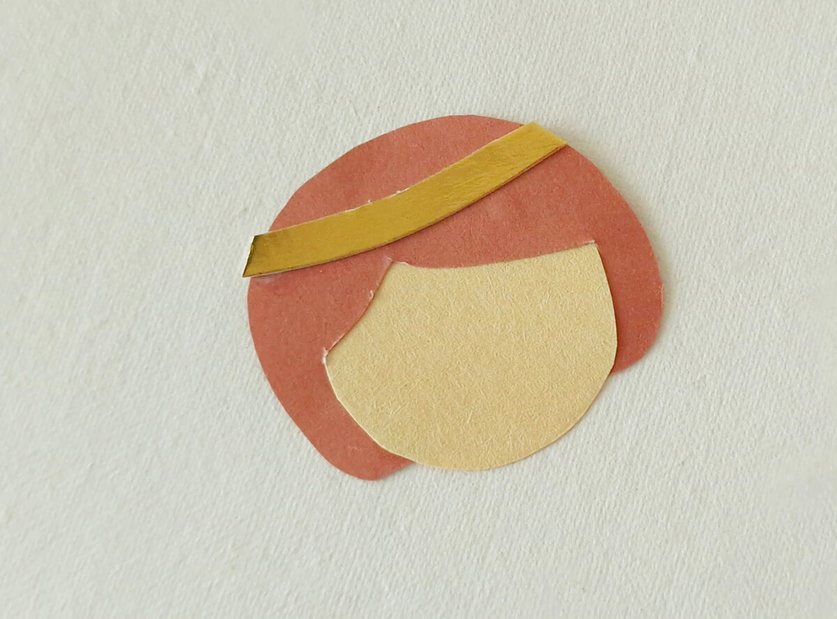 Abstract collage made of colored paper cutouts resembling a face with a red circular shape, a beige oval, and a gold strip on a light textured background.