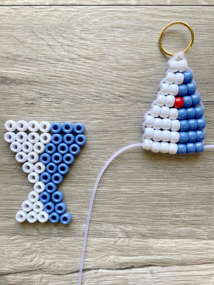 Two plastic bead crafts on wood: one shaped like a blue and white martini glass, the other cone-shaped with a key ring and a pattern of blue, white, and one red bead.